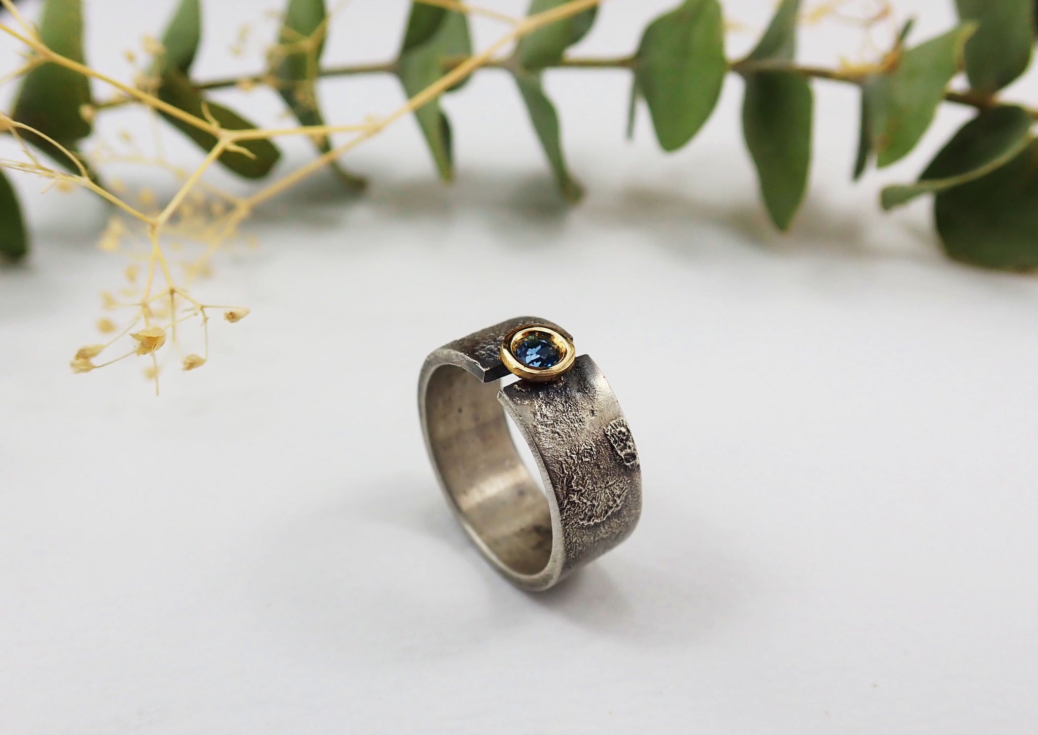 Anillo de plata con textura, oro de 18 kt y topacio azul