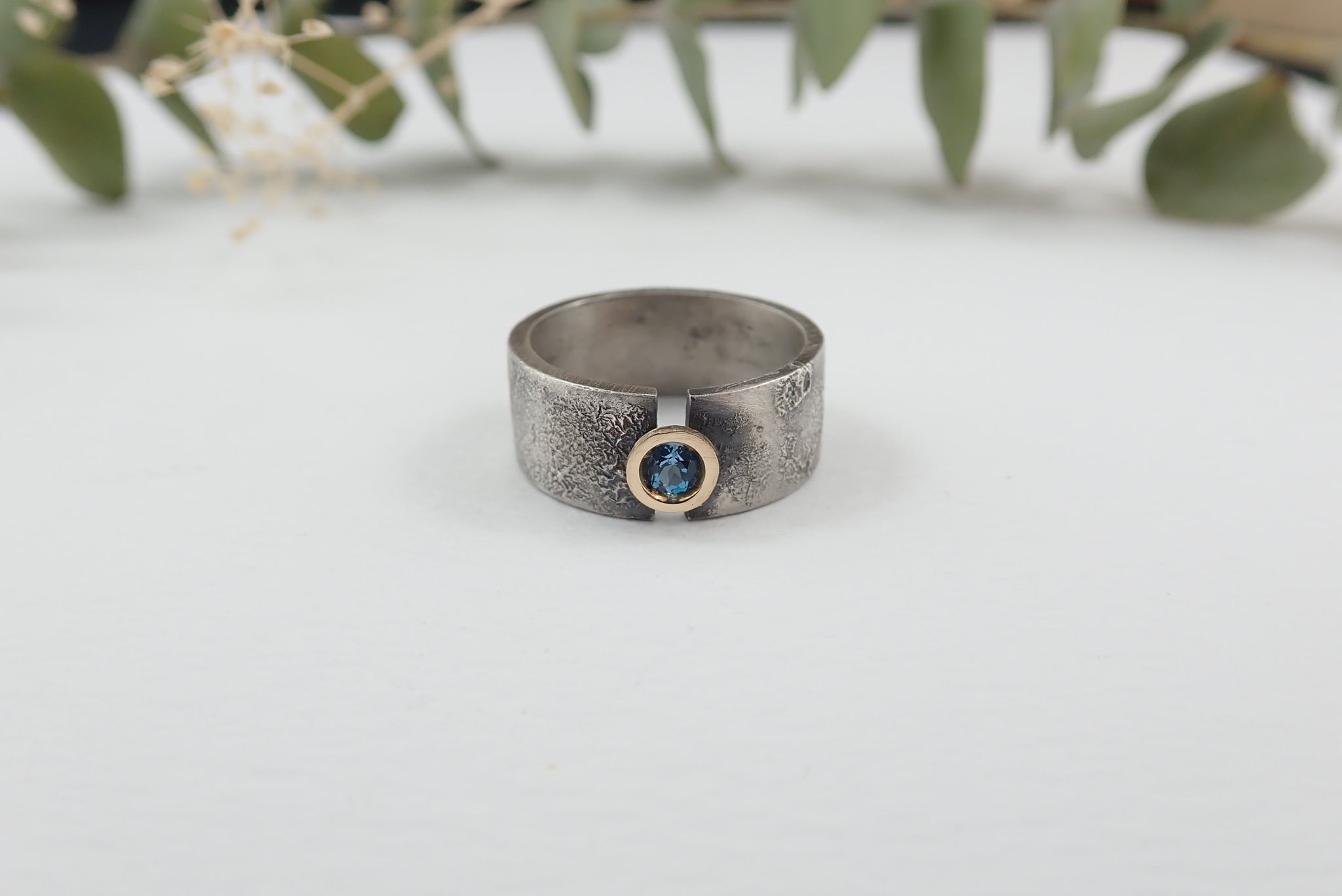 Anillo de plata con textura, oro de 18 kt y topacio azul