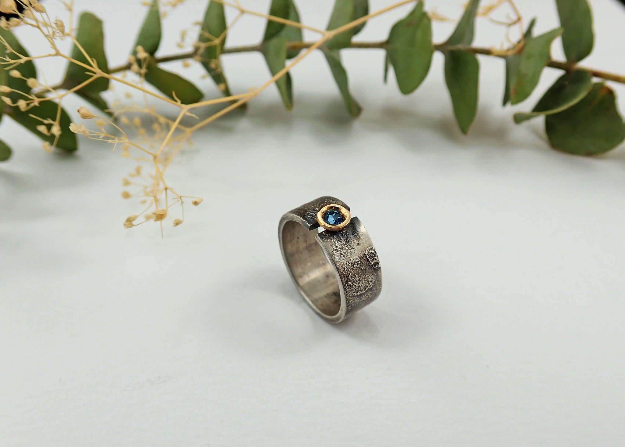 Anillo de plata con textura, oro de 18 kt y topacio azul